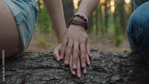 couple holding hands sitting on log in forest boyfriend and girlfriend sharing romantic connection in woods happy young lovers photo