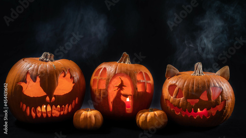 Illuminated jack o lantern halloween pumpkins, on black background	