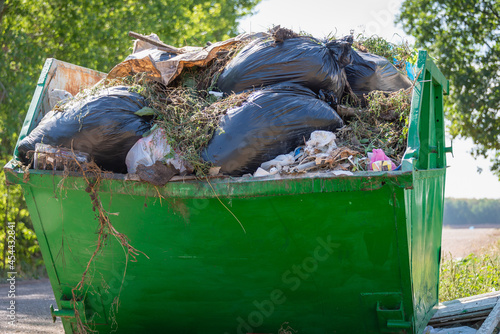 Metal container with rubbish. There are garbage bags in the container.