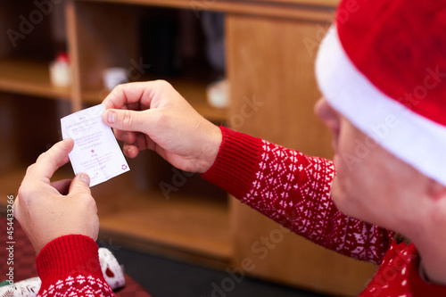Canvas Print Man in santa hat and red jumper reading christmas cracker joke
