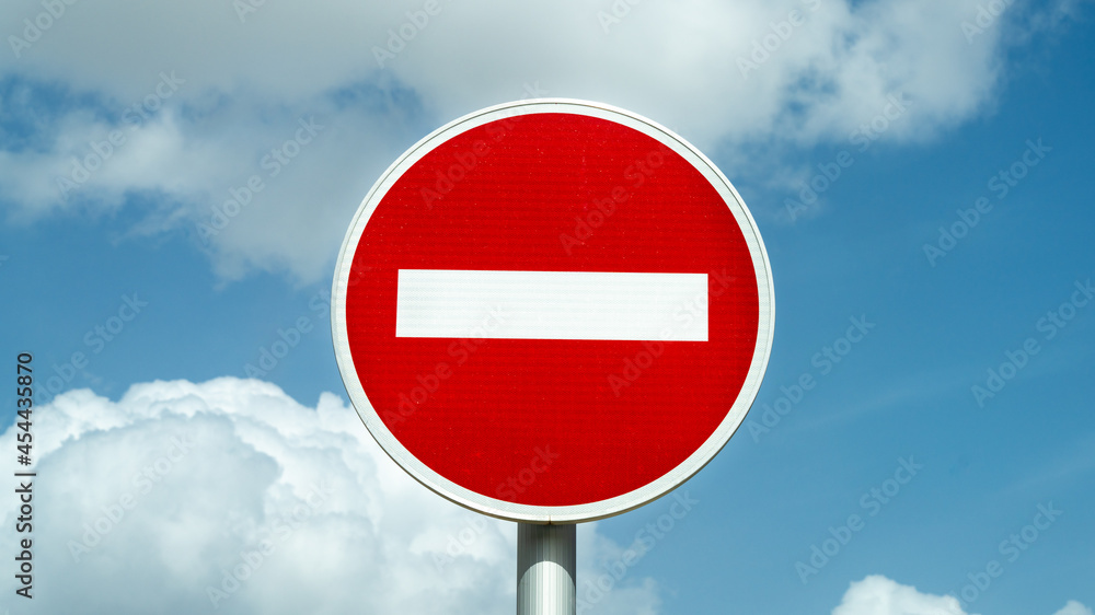 Close-up on a traffic sign, forbidden, against a background of blue sky with white cottony clouds Close-up on a traffic sign, forbidden, against a background of blue sky with white cottony clouds
