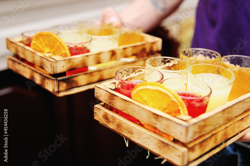 Sets of different liquors in wooden boxes in the hands of the waiter