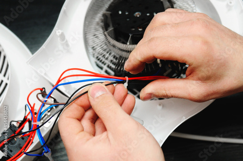 The electrician repairs the electric heater. Details of household appliances. Male hands repair the heater.