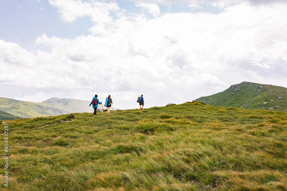 mountain hiking concept. vacation in the mountains. three people walking on top of a mountain