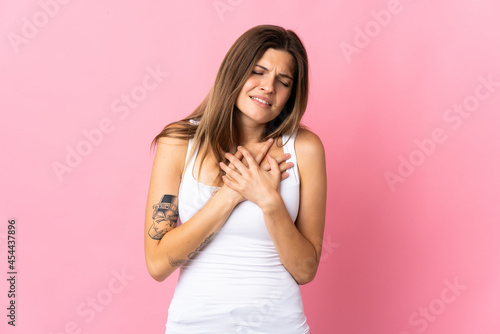 Young slovak woman isolated on pink background having a pain in the heart
