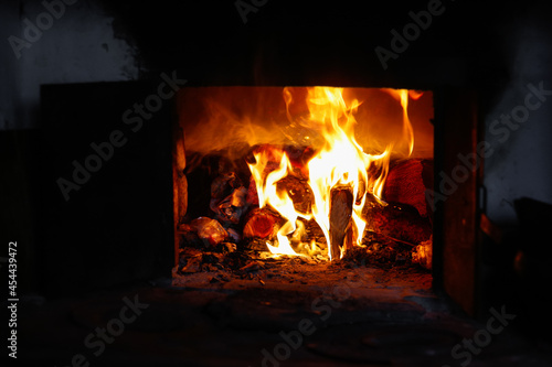 Defocus fire flame background. Firewood burning in old stove or oven. Dark and black. Orange flame. Heat energy. Open iron door. Rustic house. Out of focus