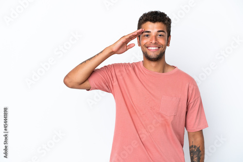 Young handsome Brazilian man isolated on white background saluting with hand with happy expression