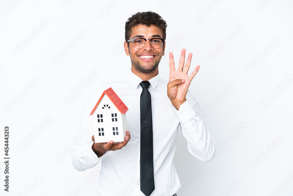 Young business Brazilian man holding a house toy isolated on white background happy and counting four with fingers Young business Brazilian man holding a house toy isolated on white background happy and counting four with fingers