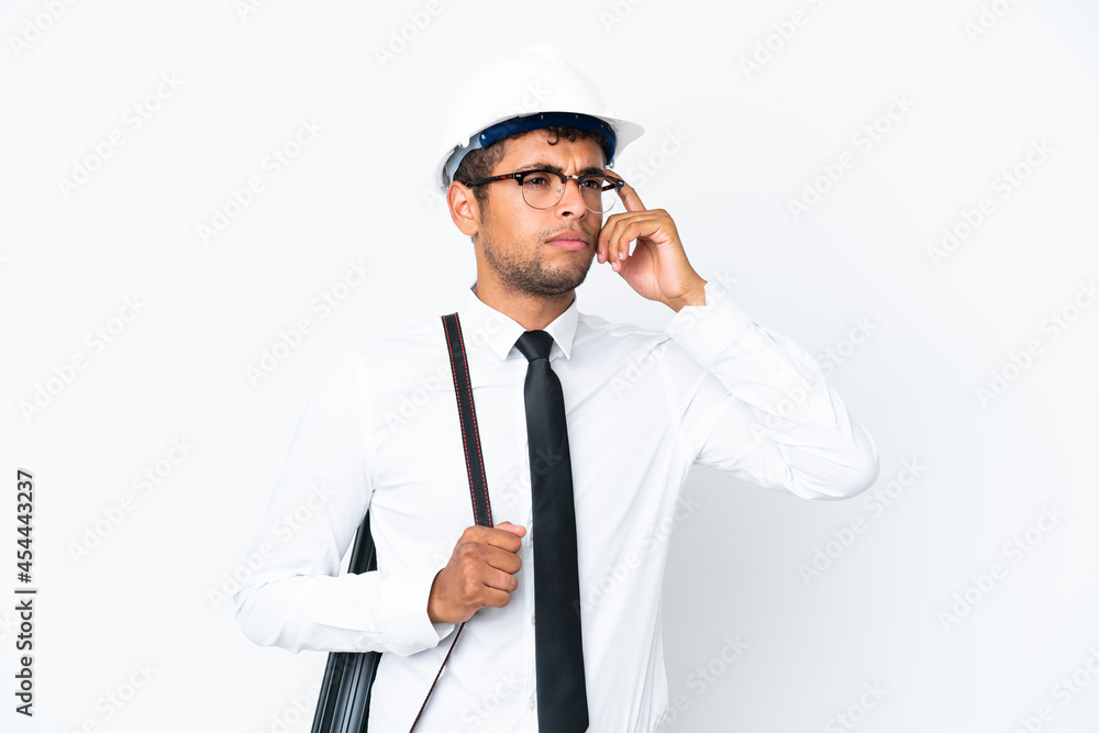 Architect brazilian man with helmet and holding blueprints having doubts and thinking Architect brazilian man with helmet and holding blueprints having doubts and thinking