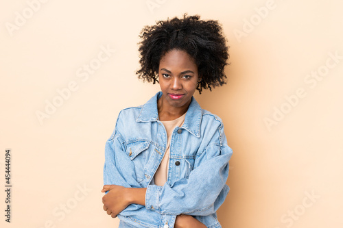 Young African American woman isolated on beige background with sad expression