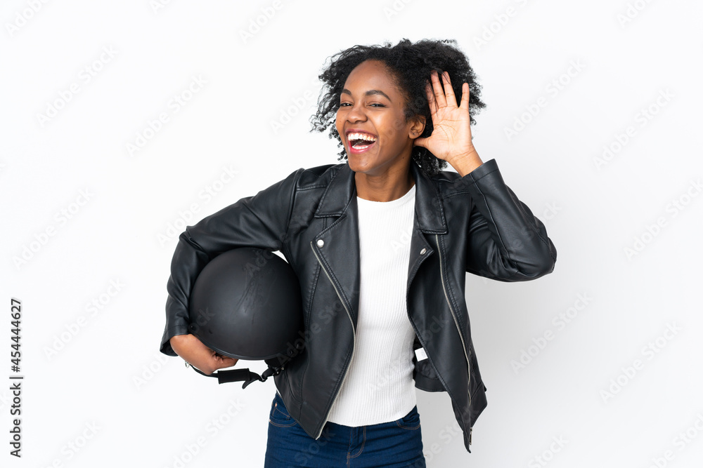 Young African American woman with a motorcycle helmet isolated on white background listening something Young African American woman with a motorcycle helmet isolated on white background listening something