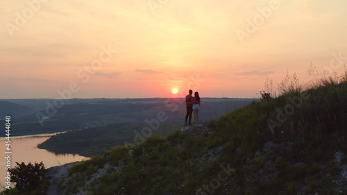 The romantic couple standing on mountain slope against the beautiful sunset