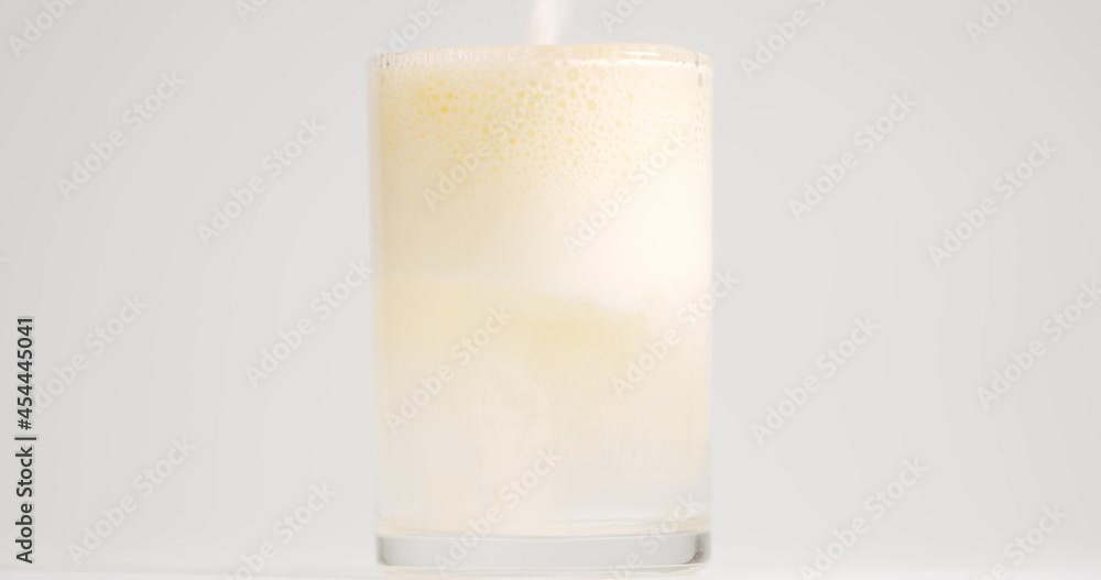 Close-up detail Front view, pour the powder antacid vitamin falling down in glass with bubbles effervescent on White background. Close-up detail Front view, pour the powder antacid vitamin falling down in glass with bubbles effervescent on White background.
