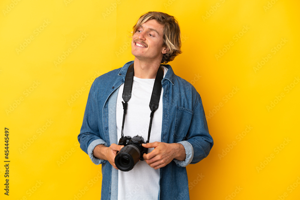 Young photographer man isolated on yellow background looking to the side and smiling Young photographer man isolated on yellow background looking to the side and smiling