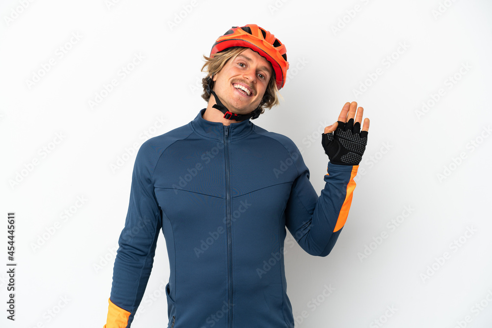 Young blonde cyclist man isolated on white background saluting with hand with happy expression Young blonde cyclist man isolated on white background saluting with hand with happy expression