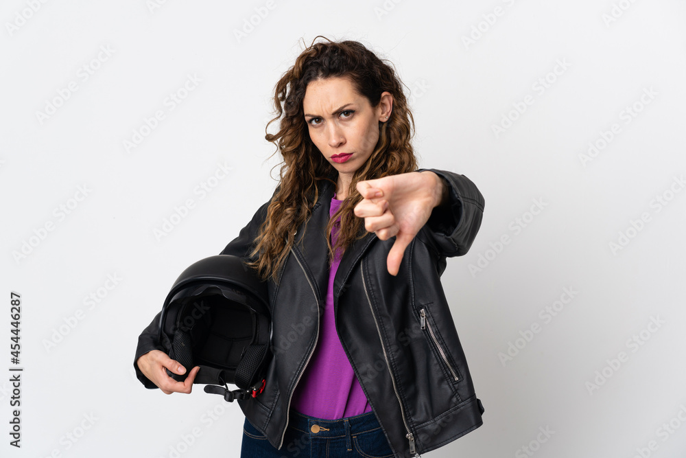 Young caucasian woman holding a motorcycle helmet showing thumb down with negative expression Young caucasian woman holding a motorcycle helmet showing thumb down with negative expression