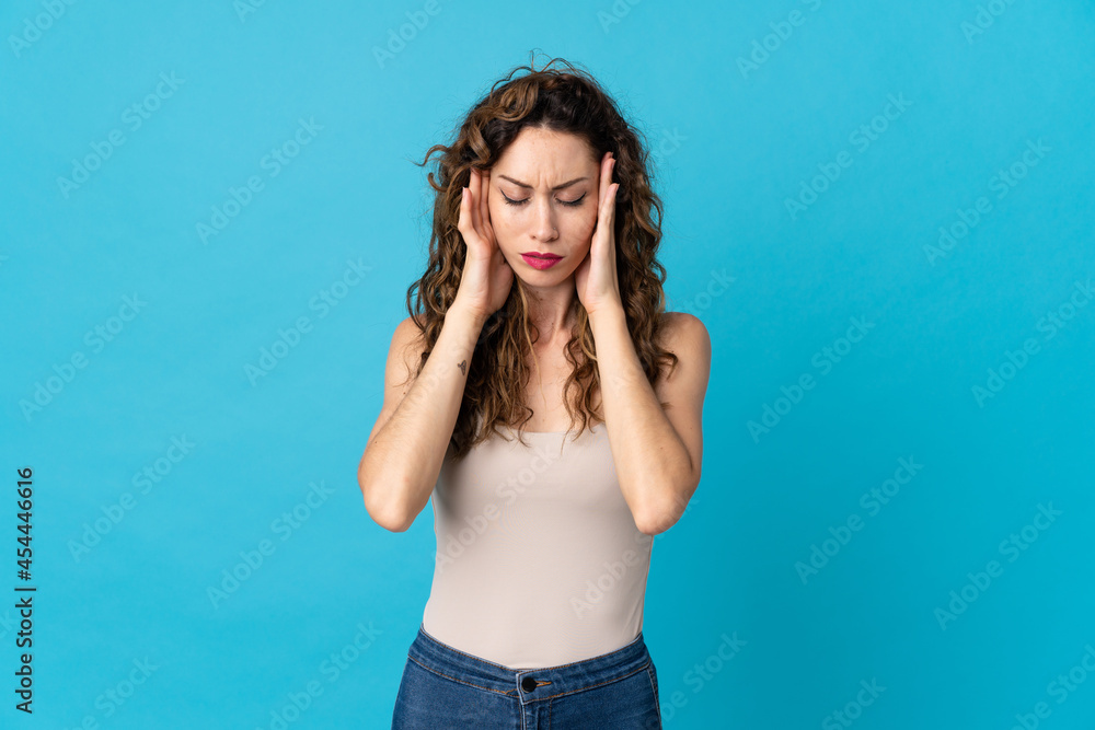 Young caucasian woman isolated on blue background with headache