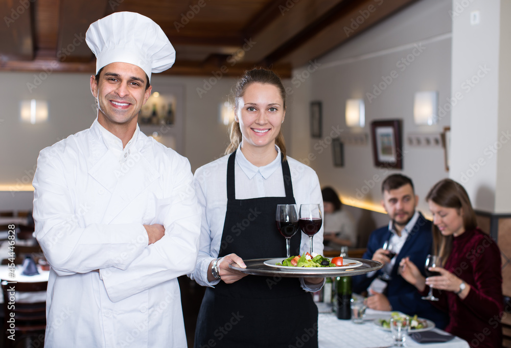 Portrait of confident man chef and smiling waitress in cafe.