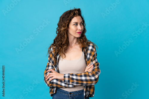 Young caucasian woman isolated on blue background keeping the arms crossed © luismolinero