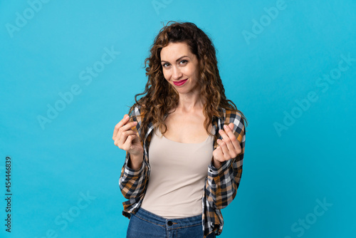 Young caucasian woman isolated on blue background making money gesture © luismolinero