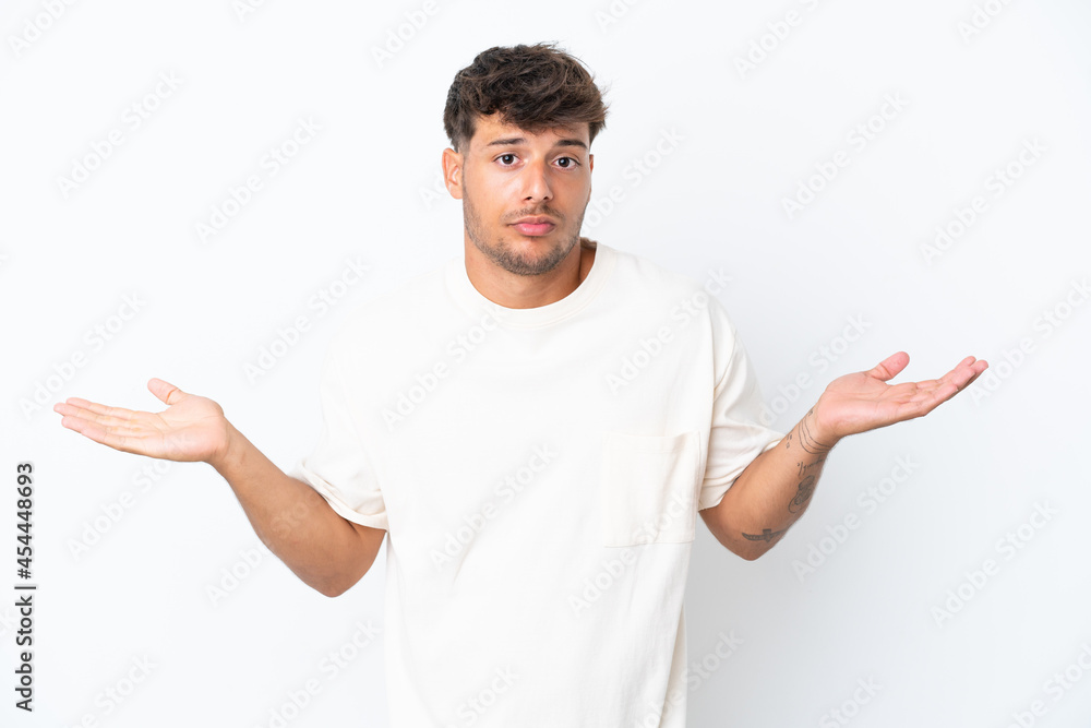 Young caucasian handsome man isolated on white background having doubts while raising hands Young caucasian handsome man isolated on white background having doubts while raising hands