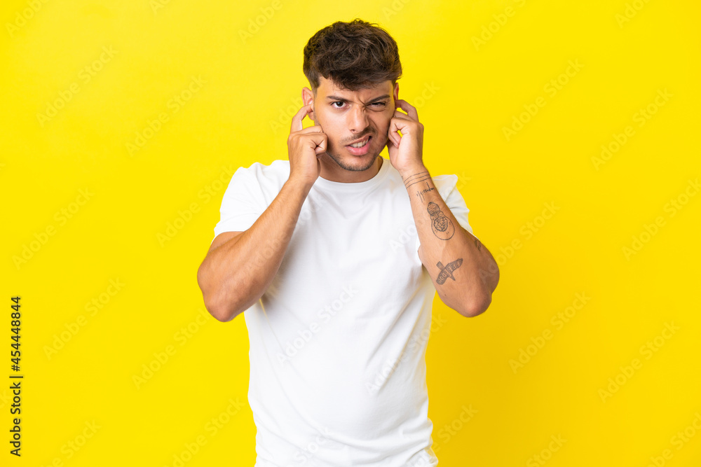 Young caucasian handsome man isolated on yellow background frustrated and covering ears Young caucasian handsome man isolated on yellow background frustrated and covering ears