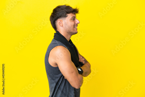 Young sport caucasian man with towel isolated on yellow background in lateral position © luismolinero