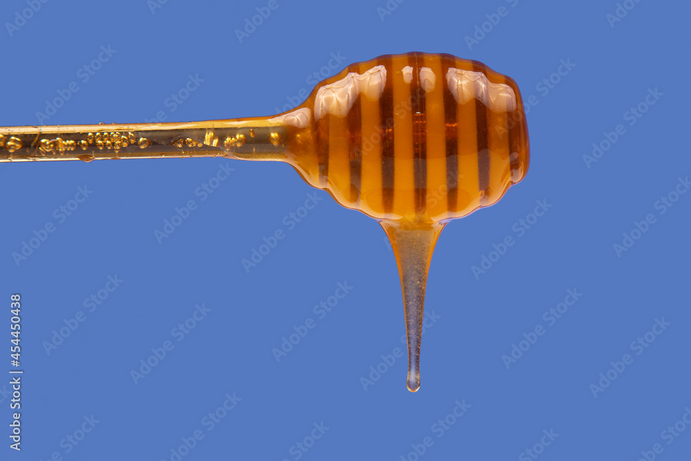 fresh honey dripping from a spoon on a blue background. organic vitamin health food fresh honey dripping from a spoon on a blue background. organic vitamin health food