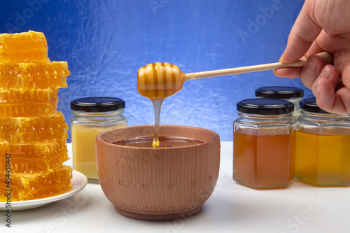 fresh honey dripping from a spoon into a plate on a blue background. organic vitamin health food