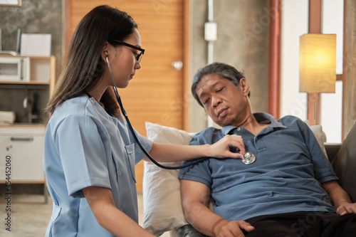 Female doctor checking the health of Asian elderly male patient at home as a medical service for visiting sick older people after retirement, medical support, residential caregiver from professional.