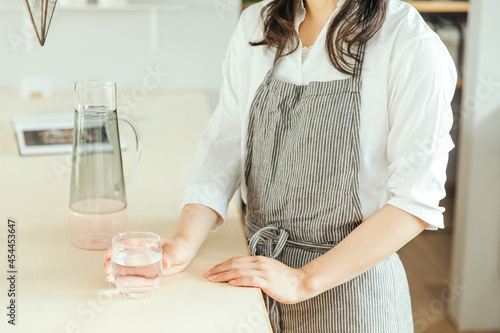 女性がキッチンで水の入ったグラスを持っている　woman water hand