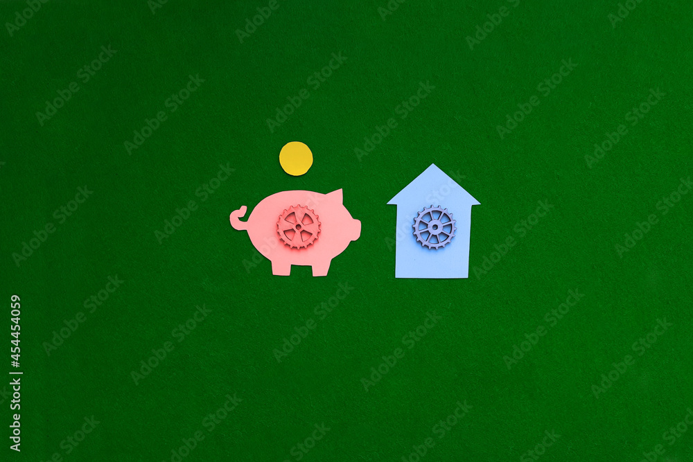 Piggy bank, gear house on a green background. The housing market. Purchase, sale of non-movable property.