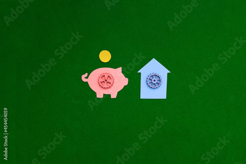 Obraz na płótnie Piggy bank, gear house on a green background. The housing market. Purchase, sale of non-movable property. w salonie
