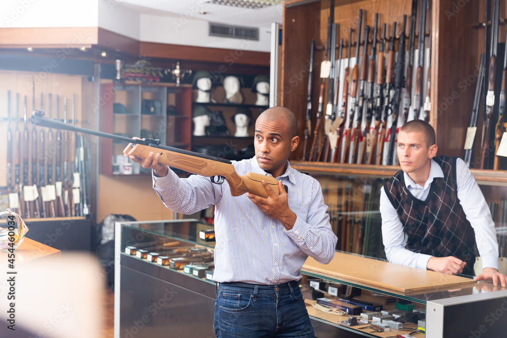 Two men choosing pneumatic weapon in military store