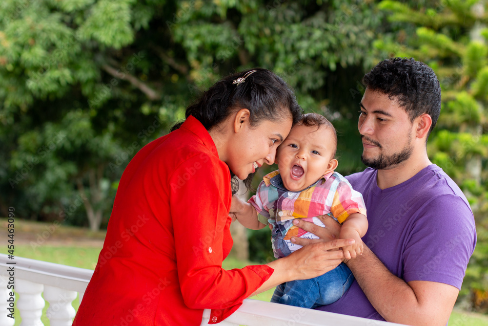 Smiling parents playing with their baby in a beautiful park full of nature. latin family concept. Smiling parents playing with their baby in a beautiful park full of nature. latin family concept.