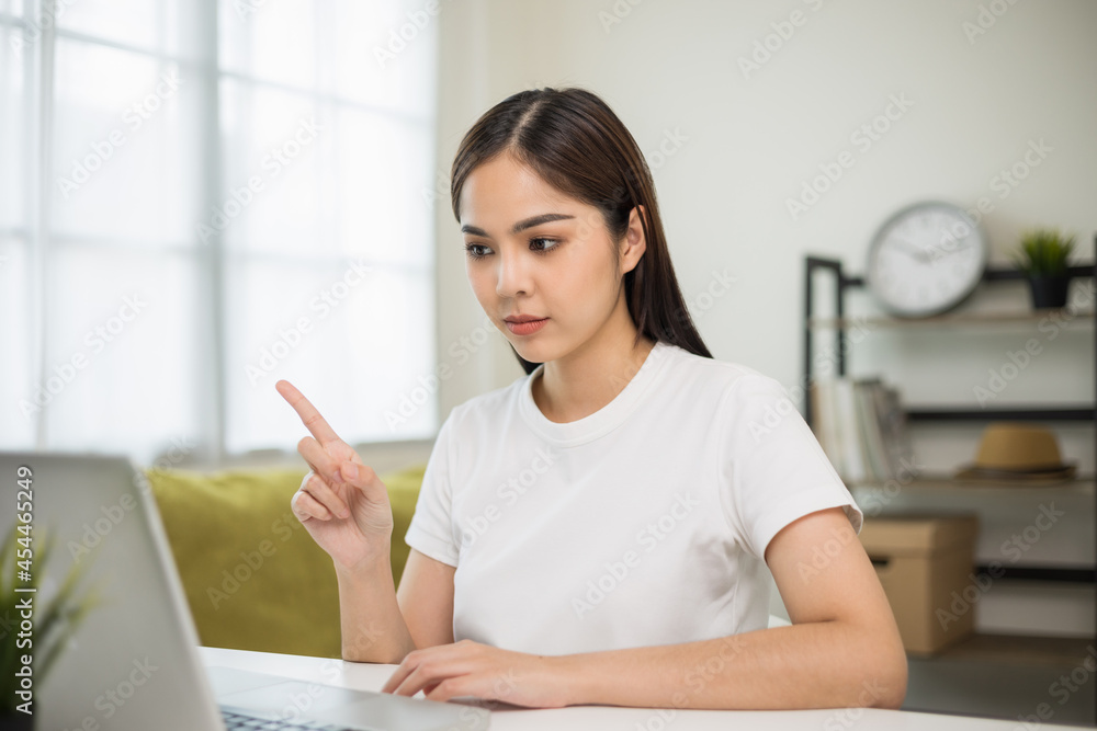 Young asian woman using laptop chatting video conference online sitting in living room at home. Business Woman looking at screen Meeting on social media live steam. Work, learning from home. Young asian woman using laptop chatting video conference online sitting in living room at home. Business Woman looking at screen Meeting on social media live steam. Work, learning from home.
