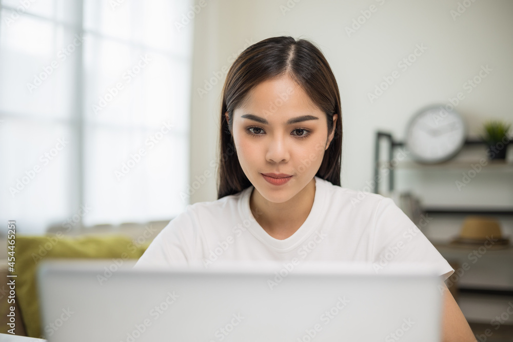 Young asian woman using laptop chatting video conference online sitting in living room at home. Business Woman looking at screen Meeting on social media live steam. Work, learning from home. Young asian woman using laptop chatting video conference online sitting in living room at home. Business Woman looking at screen Meeting on social media live steam. Work, learning from home.