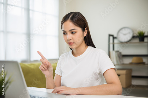 Young asian woman using laptop chatting video conference online sitting in living room at home. Business Woman looking at screen Meeting on social media live steam. Work, learning from home.