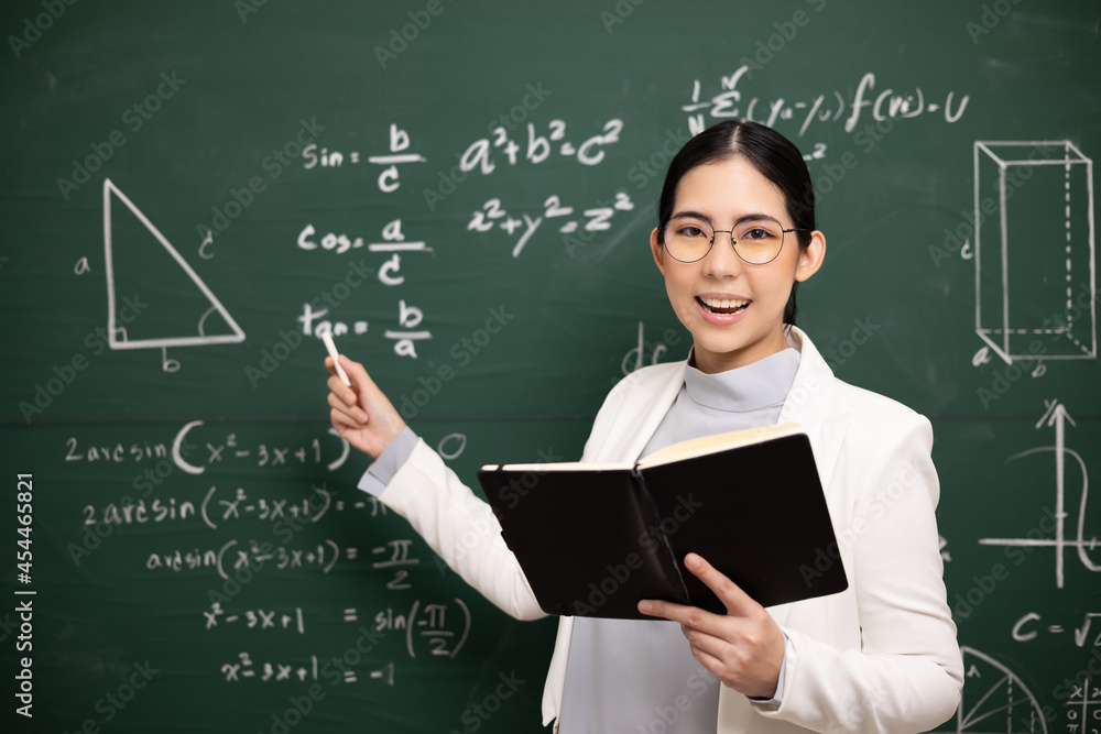 Young asian teacher woman teaching holding book and chalk video conference with student looking camera. Female teacher training the mathematics in classroom blackboard from online course. Young asian teacher woman teaching holding book and chalk video conference with student looking camera. Female teacher training the mathematics in classroom blackboard from online course.