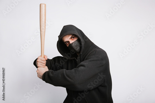 A masked bandit in a black hoodie, jeans and a bat on a white background.