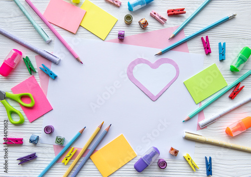 Frame of different stationery on white wooden background