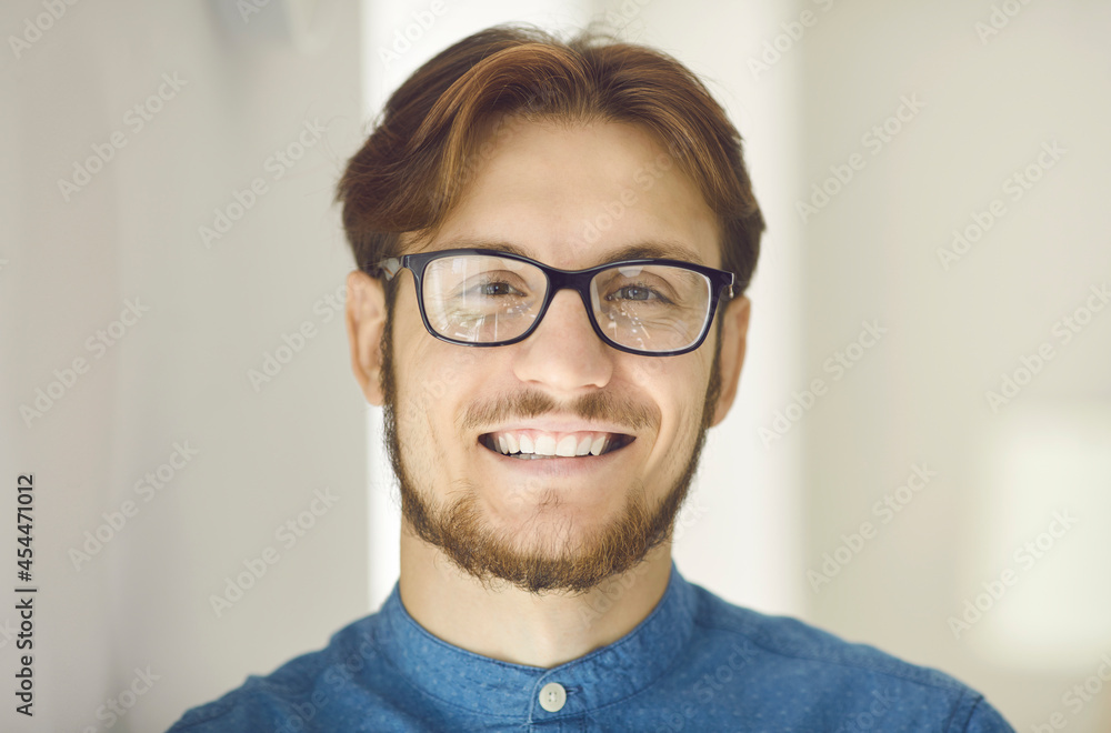 Portrait of happy clever intelligent young man in glasses looking at camera and smiling. Headshot of successful corporate worker, company employee or businessman with cheerful positive face expression Portrait of happy clever intelligent young man in glasses looking at camera and smiling. Headshot of successful corporate worker, company employee or businessman with cheerful positive face expression