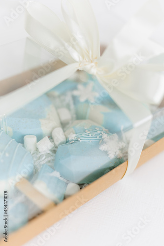 cardboard box with Christmas cakes. Different confectionery cakes of blue color. Chocolate, spruce branches, decoration in the form of snowflakes.