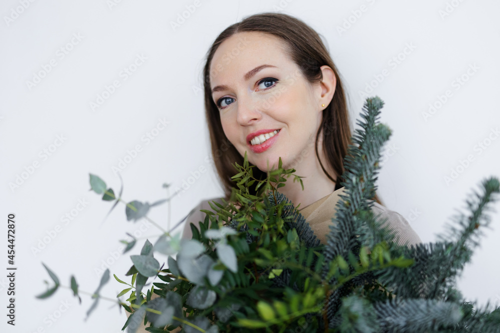 portrait of a Caucasian young woman florist with a winter bouquet in her hands. a bouquet of greenery in tap paper. Christmas and New Year. portrait of a Caucasian young woman florist with a winter bouquet in her hands. a bouquet of greenery in tap paper. Christmas and New Year.