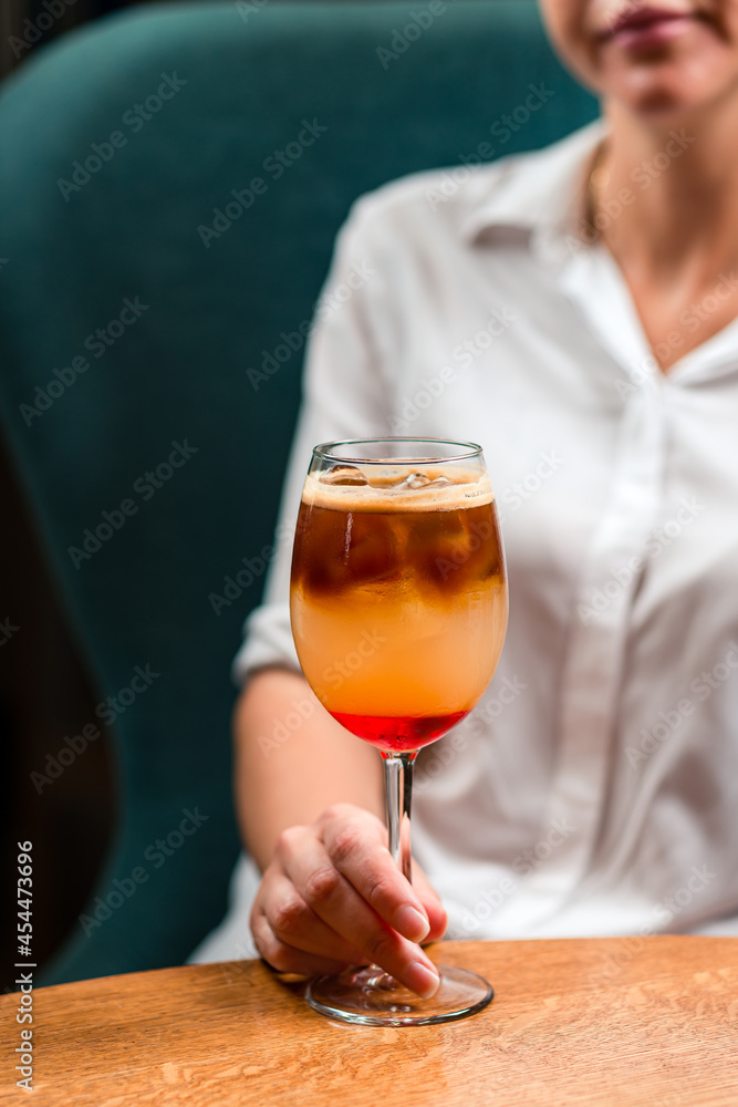 woman with a cocktail at the table, a cocktail with cold coffee and an aperol woman with a cocktail at the table, a cocktail with cold coffee and an aperol