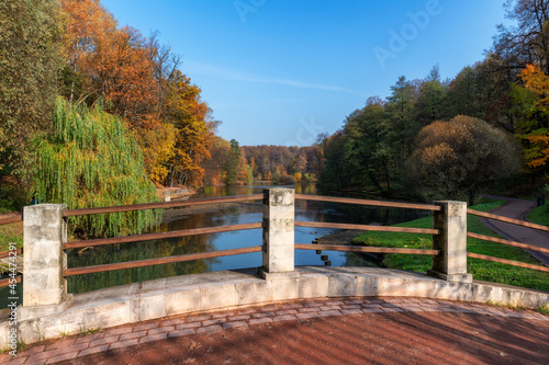 Autumn landscape from river bridge. Colorful leaves in autumn park