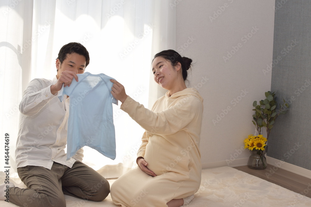 A pregnant young wife and husband are looking forward to the birth of a baby with blue baby clothes. A pregnant young wife and husband are looking forward to the birth of a baby with blue baby clothes.