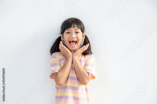 Portrait of surprised cute little toddler girl child standing isolated over white background. looking at the camera. hands near open mouth