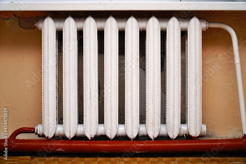 Old cast-iron radiator on the background of gray wall. Heating battery