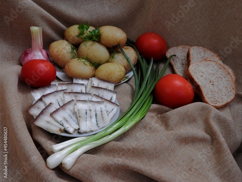 Vegetables on the table. Ingramdients for the recipe. Potatoes, tomatoes, onions, greens, bacon.